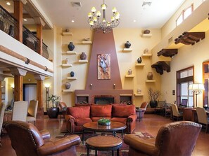 A spacious lobby with a fireplace, leather sofas, a chandelier, and a variety of decorative items on shelves. - 2 Bedroom Villa at Sheraton Desert Oasis Resort (Scottsdale)