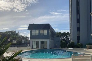 A swimming pool with a building in the background. - Holiday Towers Unit 301 (Myrtle Beach)