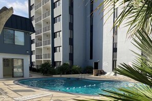 A swimming pool area with a building in the background. - Holiday Towers Unit 301 (Myrtle Beach)