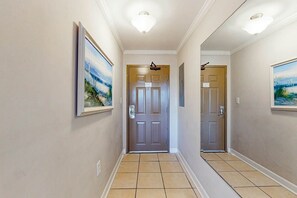 A hallway with a door at the end, a light fixture above, and a framed picture on the wall. - Meridian Plaza Unit 208 (Myrtle Beach)