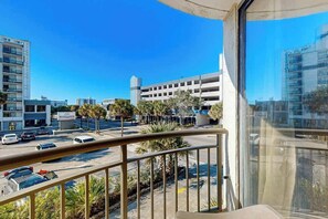 Ein Balkon mit Blick auf eine Parkgarage, ein Gebäude mit einem Schild und einem strahlend blauen Himmel.