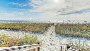 A beach with a wooden boardwalk leading to the water, surrounded by tall grasses. - Meridian Plaza Unit 208 (Myrtle Beach)
