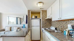A compact kitchen with a refrigerator, stove, and sink. - Meridian Plaza Unit 208 (Myrtle Beach)