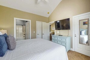 A bedroom with a bed, a dresser, a television, and a door leading to a bathroom. - Myrtlewood Golf & Beach Retreat (Myrtle Beach)