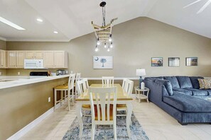 A modern kitchen with white cabinets, a dining table with chairs, and a blue sofa in a living area. - Myrtlewood Golf & Beach Retreat (Myrtle Beach)