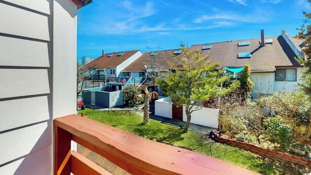 A residential area with houses, a clear sky, and a wooden balcony railing. - Brandywine South Unit 4G (Myrtle Beach)