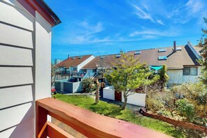 A residential area with houses, a clear sky, and a wooden balcony railing. - Brandywine South Unit 4G (Myrtle Beach)