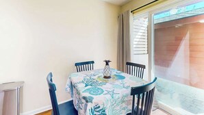 A dining area with a table covered in a tablecloth, four chairs, and a vase. - Brandywine South Unit 4G (Myrtle Beach)