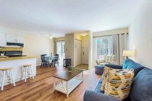 Ein moderner Wohnraum mit Küche, Essbereich und einer Sitzecke inklusive Sofa und Sesseln.