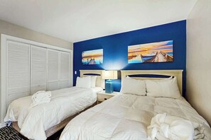 A hotel room with two beds, a closet, and two paintings on the wall. - Chelsea House Villas 112 (Myrtle Beach)