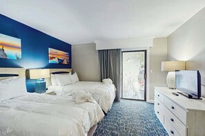 A hotel room with two beds, a television, a desk, and a view of the outdoors. - Chelsea House Villas 112 (Myrtle Beach)