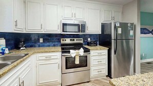 Una cocina moderna con armarios blancos, electrodomésticos de acero inoxidable y encimera de granito.