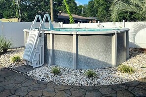A swimming pool with a ladder, surrounded by white pebbles and small plants. - Beach House Hideaway (North Myrtle Beach)