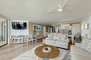 A spacious living room with a sofa, coffee table, and a TV mounted on the wall. - Surfmaster by the Sea 208 (Murrells Inlet)