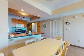 A modern kitchen with a dining area, featuring a central island, white cabinetry, and a microwave. - Harbourgate Unit 0620 (North Myrtle Beach)