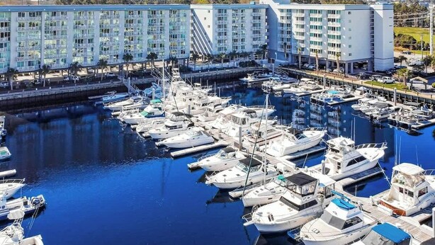 A marina with multiple boats docked, surrounded by modern buildings with balconies. - Harbourgate Unit 0620 (North Myrtle Beach)