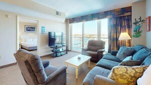 A hotel room with a sofa, armchair, TV, and a view of the outdoors. - Harbourgate Unit 0620 (North Myrtle Beach)