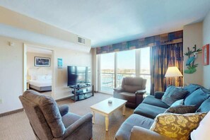 A hotel room with a sofa, armchair, TV, and a view of the outdoors. - Harbourgate Unit 0620 (North Myrtle Beach)