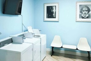 Ein Zimmer mit einer Waschmaschine, einem Schreibtisch inklusive Computer und zwei Stühlen.