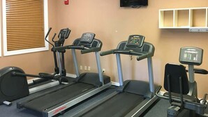 Three treadmills in a gym with a television above and a shelf with items on the wall. - Ocean Creek Lodge IV - 2287 (Myrtle Beach)