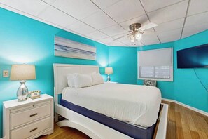 A bedroom with a bed, nightstands, a ceiling fan, a TV, and a window with blinds. - Ocean Creek Lodge IV - 2287 (Myrtle Beach)