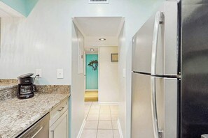 A kitchen with a stainless steel refrigerator, a coffee maker, and a teal-colored wall. - Ocean Creek Lodge IV - 2287 (Myrtle Beach)
