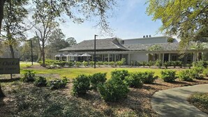 A building with a covered outdoor area, surrounded by landscaped gardens and a paved walkway. - Ocean Creek Lodge IV - 2287 (Myrtle Beach)