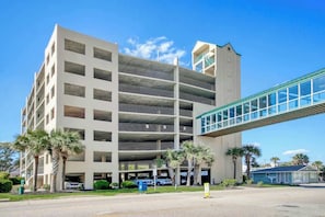 A multi-story parking garage with a glass bridge connecting to a building. - Windy Hill Dunes 204 (North Myrtle Beach)