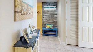 A hallway with a wooden bench, a wall-mounted picture, and a closed door. - Windy Hill Dunes 204 (North Myrtle Beach)