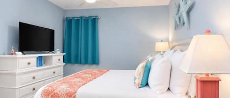 A bedroom with a bed, a television, a ceiling fan, and a starfish decoration on the wall.