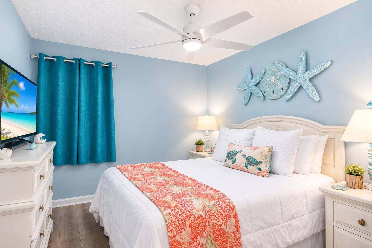 Une chambre à coucher avec un lit, un ventilateur de plafond, une table de chevet avec une lampe et un mur décoré d’une étoile de mer.