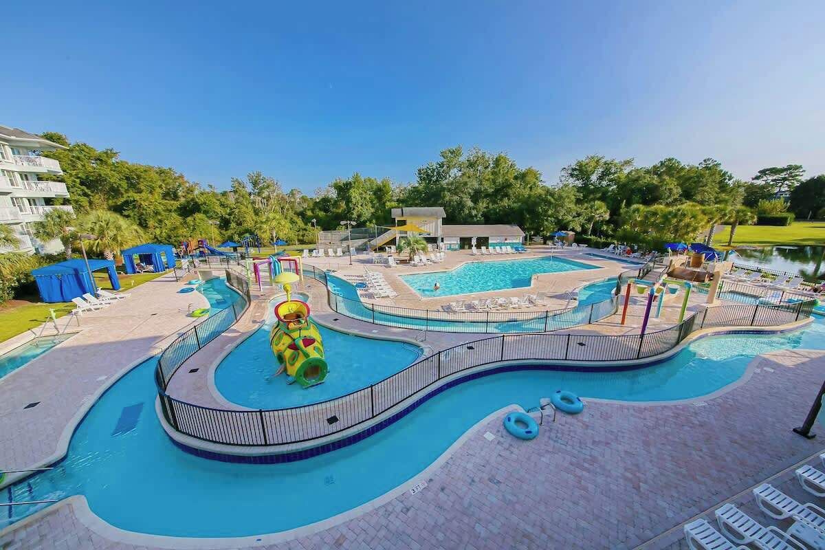 A swimming pool area with multiple lanes, a water slide, and lounge chairs.