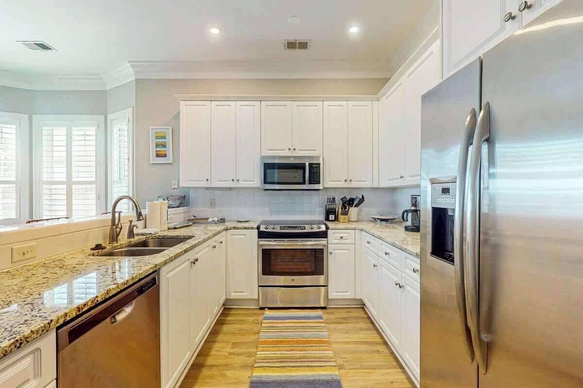 A modern kitchen with white cabinets, stainless steel appliances, and a granite countertop.