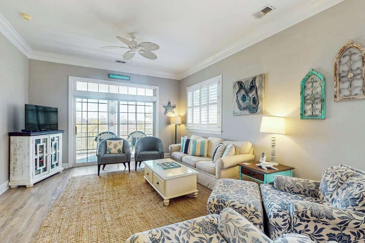 A living room with a ceiling fan, a television on a cabinet, a sofa, a coffee table, and a rug.