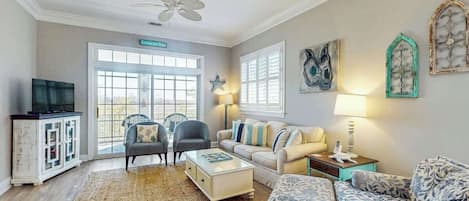 A living room with a ceiling fan, a television on a cabinet, a sofa, a coffee table, and a rug.