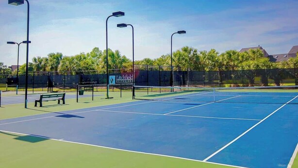 An outdoor tennis court with a bench, street lamps, and a fence. - Marsh Hawk 3D at Litchfield by the Sea (Pawleys Island)