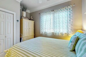 A bedroom with a bed, a wardrobe, a window with patterned curtains, and a wall-mounted lamp. - Marsh Hawk 3D at Litchfield by the Sea (Pawleys Island)