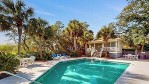A swimming pool with lounge chairs and a covered seating area surrounded by palm trees. - Marsh Hawk 3D at Litchfield by the Sea (Pawleys Island)