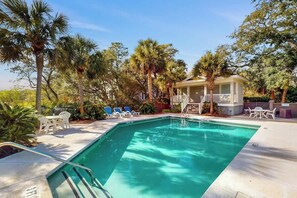A swimming pool with lounge chairs and a covered seating area surrounded by palm trees. - Marsh Hawk 3D at Litchfield by the Sea (Pawleys Island)