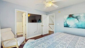 Ein Schlafzimmer mit einem Bett, einem Deckenventilator und einem Bild an der Wand.