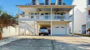 Ein zweistöckiges Haus mit verdeckter Veranda, Garage und Auffahrt.
