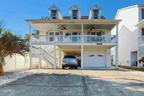 A two-story house with a covered front porch, a garage, and a driveway. - Livin' the Dream at 26th Ave N (North Myrtle Beach)