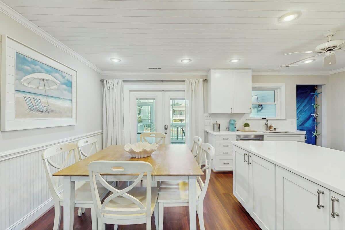 A kitchen with white cabinetry, a wooden dining table, and chairs.