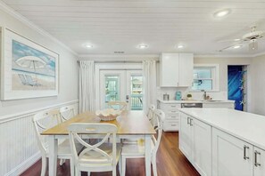 A kitchen with white cabinetry, a wooden dining table, and chairs. - Livin' the Dream at 26th Ave N (North Myrtle Beach)