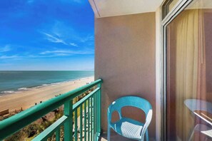 Ein Balkon mit Blick auf den Strand, ein Stuhl und ein Tisch.