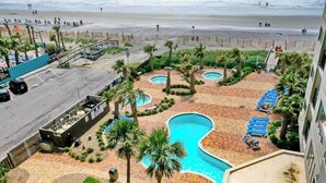 Un complexe hôtelier doté de plusieurs piscines, de palmiers et offrant une vue sur la plage.