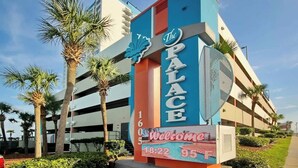 Une enseigne d’hôtel indiquant « The Palace » et affichant un message de bienvenue, ainsi que l’heure et la température.