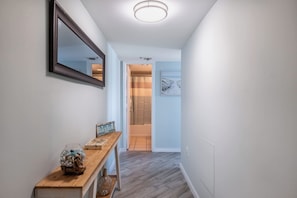 A hallway with a wooden console table, a mirror, and a framed picture on the wall. - Palace Resort Unit 1604 (Myrtle Beach)