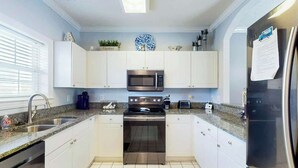 A modern kitchen with white cabinets, stainless steel appliances, and a granite countertop. - Wedgewood Unit 423 Condo (North Myrtle Beach)