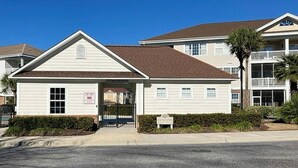 A two-story building with a flat roof, a front entrance, and a sign indicating a no parking zone. - Wedgewood Unit 423 Condo (North Myrtle Beach)